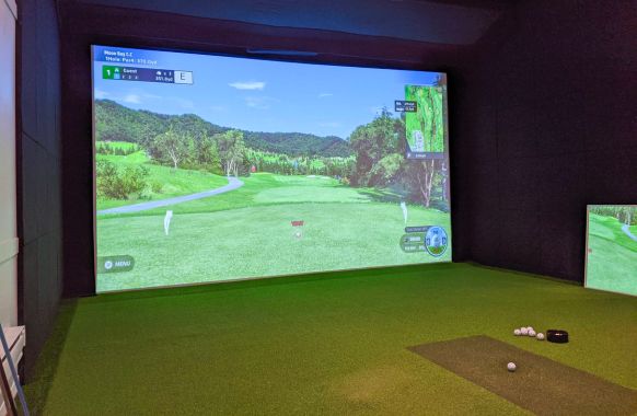 Residential golf simulator with wall padding and strike mat